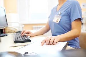 A healthcare worker entering data into an EHR.