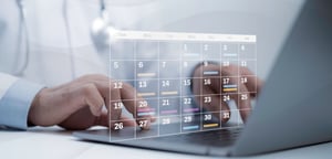 A healthcare professional reviewing a calendar on their laptop.